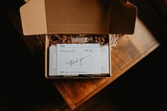 an open box with writing on it sitting on top of a wooden table next to a window