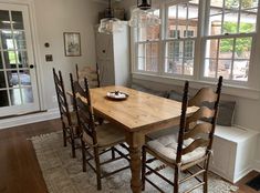 a dining room table with six chairs in front of a window and a bench next to it