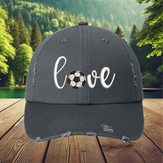 This hat is 100% cotton, soft and unstructured 6-panel low-fitting hat. One size fits most adult,Garment Washed Pigment Dyed Cotton Twill. Show your love for soccer with this stylish distressed baseball cap, featuring the word 'Love' with a soccer ball replacing the 'O'. Whether you're a player, a soccer mom, or just a fan of the beautiful game, this cap is a great way to express your passion. The distressed look gives it a trendy, vintage vibe, making it perfect for casual wear on game day or any day. Perfect for: Soccer fans, players, soccer moms, and gifting Whether you're at a soccer match or just running errands, this cap is the perfect accessory to show off your love for the sport. It also makes a great gift for soccer players, fans, or moms who are always cheering from the sidelines Casual Baseball Cap Gift, Casual Adjustable Dad Hat For Sports Events, Adjustable Casual Fitted Hat For Sports Events, Adjustable Sports Fan Hat With Curved Visor, Sports Fan Hats With Letter Print And Curved Brim, Sports Fan Cap Hat One Size Fits Most, Sports Fan Cap One Size Fits Most, Casual Adjustable Baseball Cap For Gift, Casual Baseball Cap As Gift