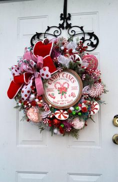 a christmas wreath on the front door with candy canes and candies around it