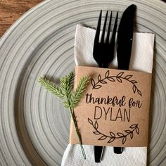 a place setting with a napkin and fork on it, decorated with an olive sprig