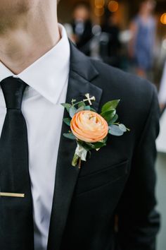 a man wearing a suit and tie with a boutonniere on his lapel