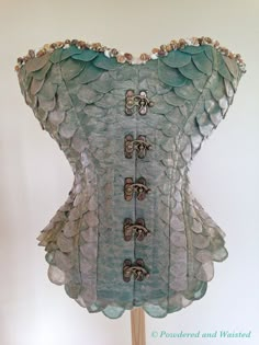 a blue corset on a wooden stand with buttons and sequins in it