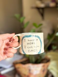 a person holding a coffee mug with writing on it that says i have a hero, i call him dad