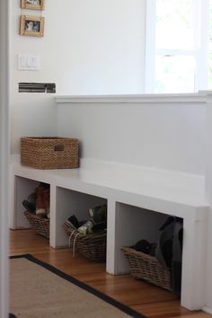 a white shelf with baskets on top of it and some pictures hanging above the shelves