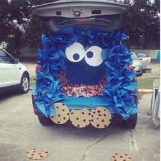 the back end of a car decorated with blue tissue paper and cookie cookies, sitting in a parking lot