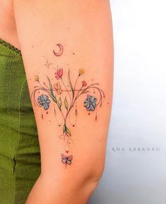 a woman's arm with flowers on it and a crescent moon behind the arm