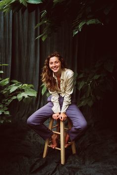 a woman sitting on top of a wooden stool