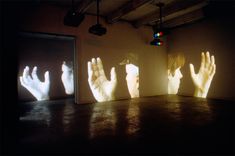 three projected images of hands on a wall