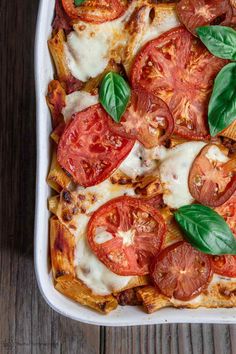 a close up of a pizza with tomatoes and basil on it's toppings