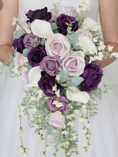 a bride holding a bouquet of purple and white flowers