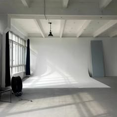 an empty photo studio with white walls and black drapes on the window sill