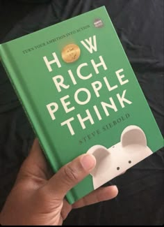 the book how rich people think by steve sebold is held in front of a black background