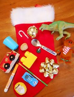 a red christmas stocking with toys and other items on it sitting on a wooden floor