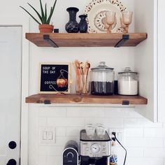 two open shelves above a coffee maker and other kitchen items on top of the counter