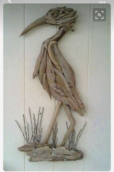 a bird made out of driftwood is hanging on the side of a wall,