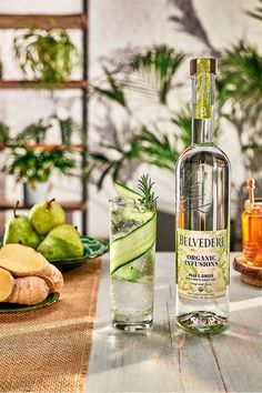 a bottle of alcohol sitting next to a glass filled with cucumber slices