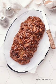 a piece of meat sitting on top of a white plate next to a knife and fork