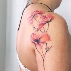 the back of a woman's shoulder with flowers painted on her arm and chest