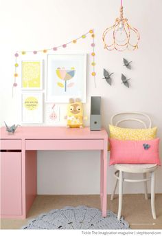 a pink desk and chair in a room with pictures on the wall above it,