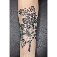 a black and white tattoo with flowers on the arm, which has fruit in it