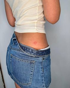 Minimalistic style red heart tattoo located on the hip. Red Heart Matching Tattoo, Fine Like Heart Tattoo, Small Heart On Hip Tattoo, Simple Red Heart Tattoo, Minimalist Red Heart Tattoo, Heart Tattoo On Hip Bone, Tiny Heart Hip Tattoo, Heart On Back Tattoo, Red Outline Heart Tattoo