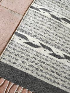 an area rug with fringes on top of it and a brick floor in the background