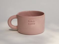 a pink ceramic mug with the words magic maker on it's front and side