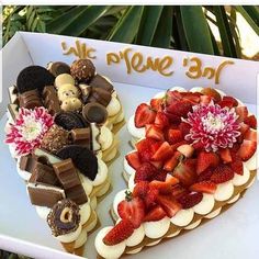 two heart shaped cakes with strawberries and chocolates on top in a cardboard box