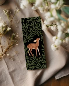 a bookmark with an image of a deer on it and flowers in the background