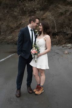 a man in a suit and tie standing next to a woman wearing a white dress