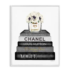 a chanel perfume bottle sitting on top of three stacked books with flowers in it