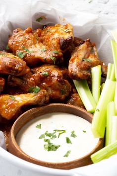 chicken wings and celery sticks in a bowl with ranch dressing on the side