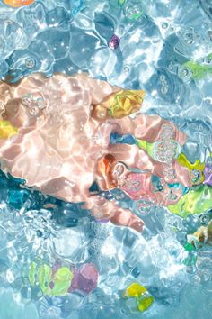 a baby in the water surrounded by bubbles and other things that are floating on top of it