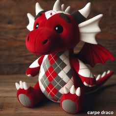 a red dragon stuffed animal sitting on top of a wooden table next to a wall