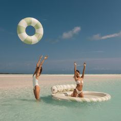 two women are playing in the water on an inflatable raft with a life preserver