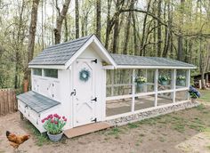 a white chicken coop in the middle of a yard with flowers and wreaths on it