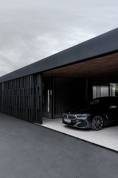 a black car is parked in front of a building with large windows and doors on the side