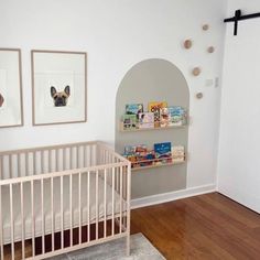 a baby's room with a crib, bookshelf and pictures on the wall