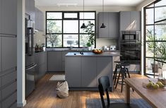 a modern kitchen with gray cabinets and wood flooring is pictured in this image, there are two bar stools at the center of the island