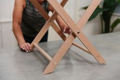 a woman sitting at a table with a wooden folding chair on it's legs