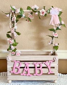 a baby crib with pink flowers and greenery on the sides, along with a name sign that says baby