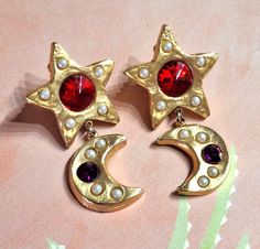 ♥Vintage signed Don-Lin clip earrings, chunky matte gold tone stars with dangling quarter moons. These earrings are embellished with red glass rhinestones and white faux pearls. These earrings are in very good condition and measure 2 7/8 inches long by 1.5 inches wide. They are fairly heavy earrings. I have replaced the jump ring that attaches the moon dangles to the stars on both earrings so they are fresh and durable and a better match. Fancy them for yourself or as a gift for a special someon Heavy Earrings, Upcycled Jewelry, Red Glass, Matte Gold, Stars And Moon, Vintage Signs, Vintage Earrings, Faux Pearl