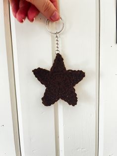 a hand holding a keychain with a brown star shaped object hanging from it's side