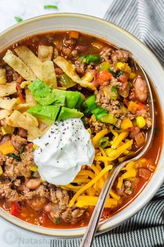 a white bowl filled with taco soup and tortilla chips on the side