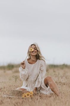 a woman sitting in the middle of a field with her face painted like a sunflower