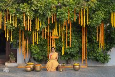 a woman sitting on a bench in front of a tree with yellow flowers hanging from it