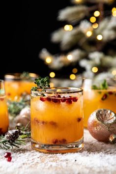 two glasses filled with orange juice and garnished with cranberries on a table