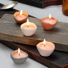 four small candles sitting on top of a wooden tray