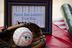 a baseball glove and ball sitting on top of a red table cloth covered tablecloth